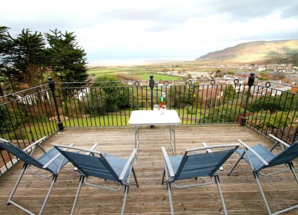4 canvas chairs on a large deck face far reaching views across Porlock Vale to the sea.