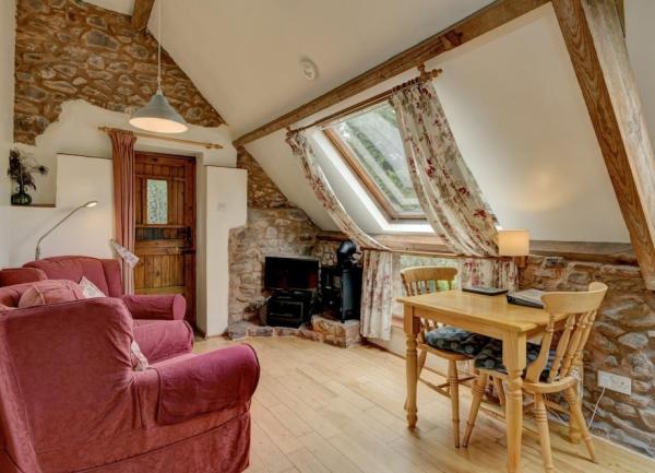 A 1st floor lounge with exposed stone walls and pine floorboards, dining table for 2 and 2 armchairs.