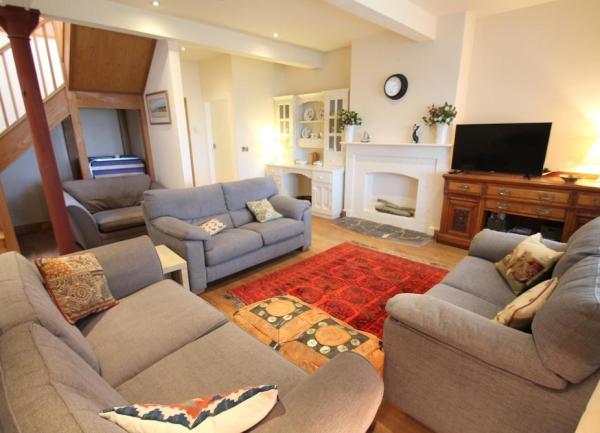 A lounge with 3 matching sofas, sideboard and TV.