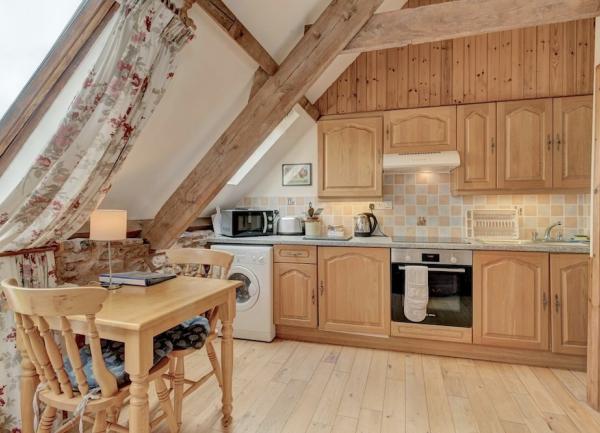 A table for 2 in front of a fitted kitchen with pine units and domestic appliances.