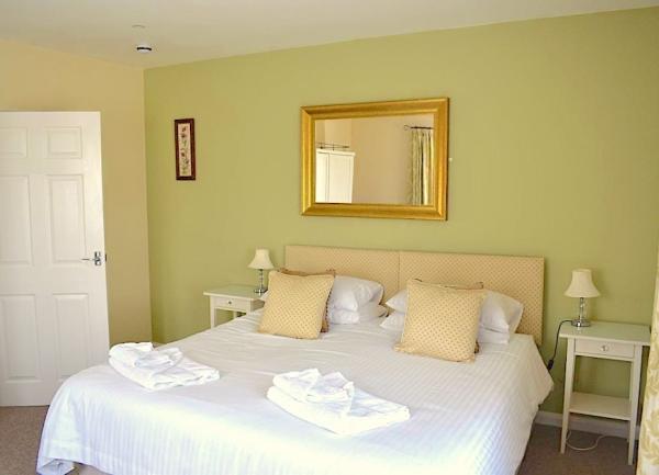 Double bedroom with bed, twin bedside tables with table lamps and a wall mirror.