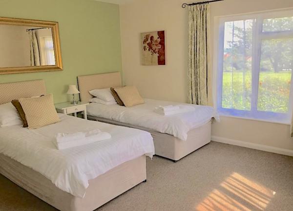 Twin bedroom with beds, wall mirror and bedside tables with lights.