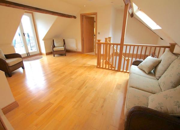 A spacious , pine-floored loft conversion with sofas and easy chairs.