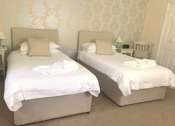 Twin bedroom with beds, each with towel sets, bedside tables and lights.