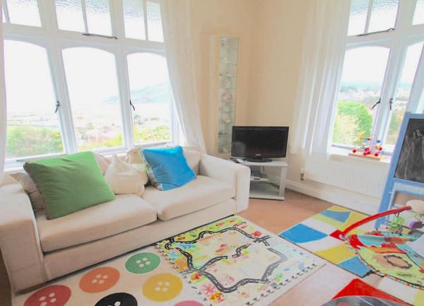 Dual aspect children's lounge with sea views with a TV and floor games.