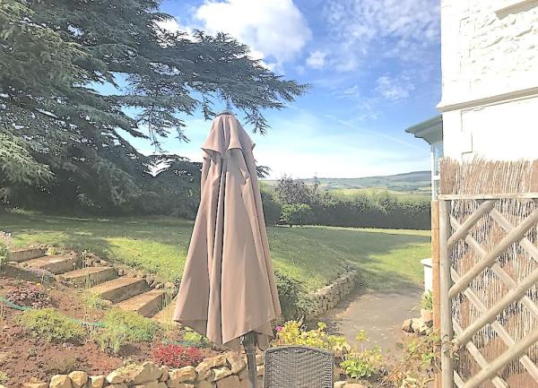 A BBQ patio leads to a large lawn.