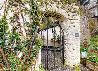 An arch in a wall leads to a courtyard of an Exmoor holiday cottage.