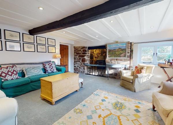 .A spacious Exmoor cottage lounge with cosy sofas and an inglenook fireplace.
