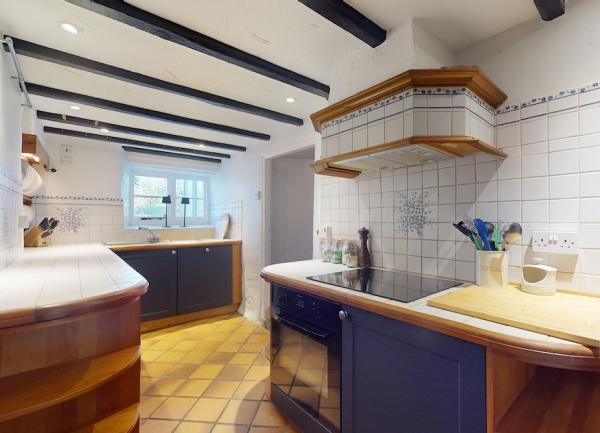 An Exmoor farmhouse kitchen with an oak-beamed ceiling and a modern oven.