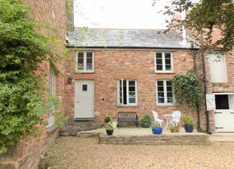 Stone-built terraced farm cottage in Somerset overlooking a courtyard.