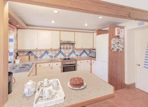 A U-shaped country cottage kitchen with fitted units and integrated white goods.