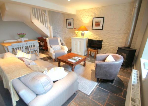 An Exmoor farm cottage living room with sofa, armchairs, TV and dinning table for four guests.