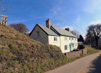 An Exmoor Longhouse overlooks a quiet, steep-banked country lane.