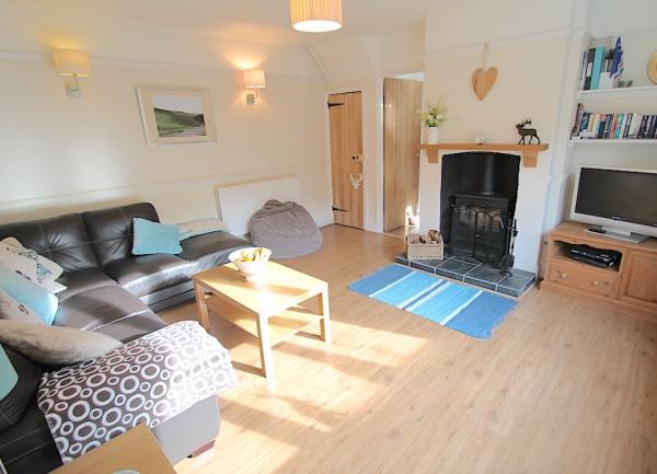 A cosy lounge with sofa, armchair, woodburner and TV