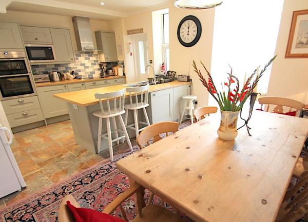 A fitted kitchen with breakfast bar and a pine-wood dining table seating 6.
