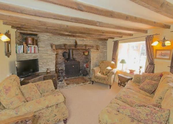 Oak-beamed Exmoor cottage lounge with inglenook, sofas and armchairs.