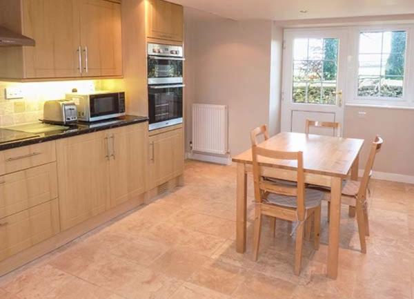 A kitchen with mid-height oven, microwave and breakfast table