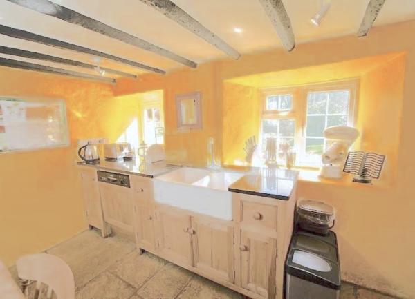 Country cottage kitchen with oak beams and butler sink and dishwasher.