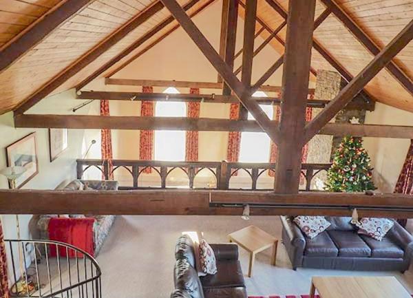 A large lounge with oak-beam trusses and leather sofas.