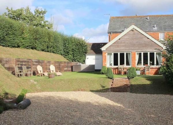 Exterior of a Devon village cottage with a patio and a well-kept garden.