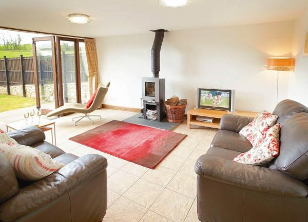 Living area with bi-fold windows, sofas, wood burner and TV.