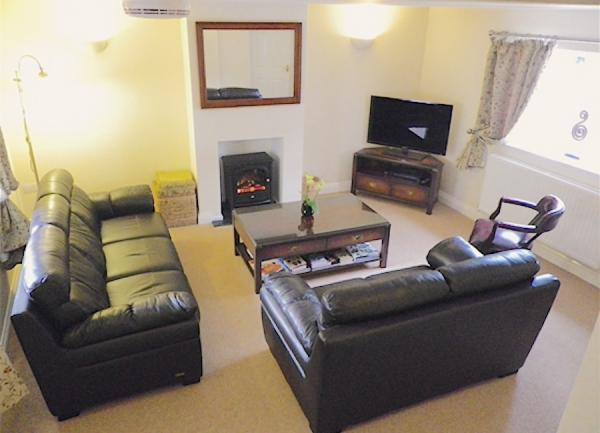 Lounge with two leather sofas, coffee table, TV and wood burner.