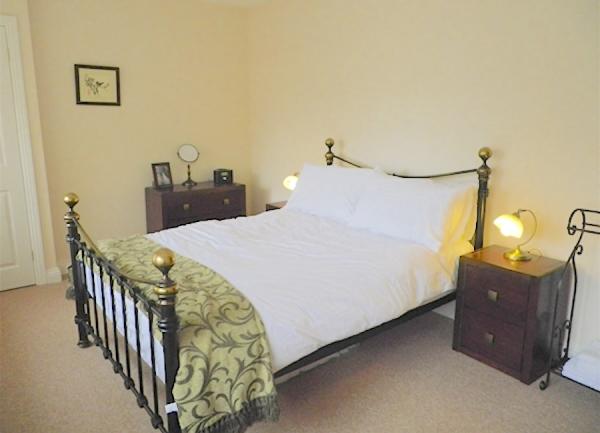Double bedroom with bed and twin bedside cabinets with table lamps.
