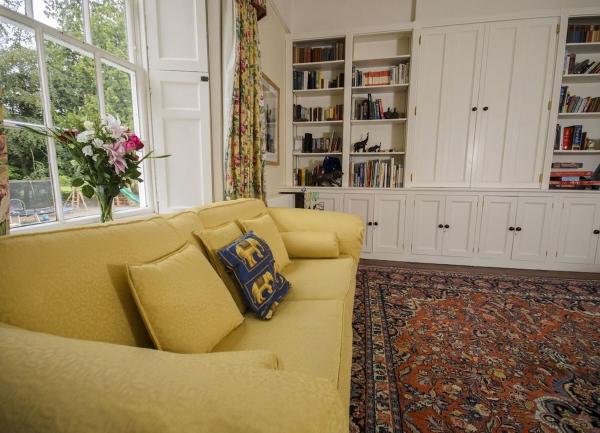 Lounge corner with sofa and 2 sets of built in bookshelves full of books.