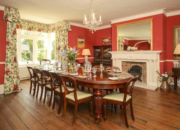 Grand oak-floored dining room with a large antique table laid for a formal dinner.