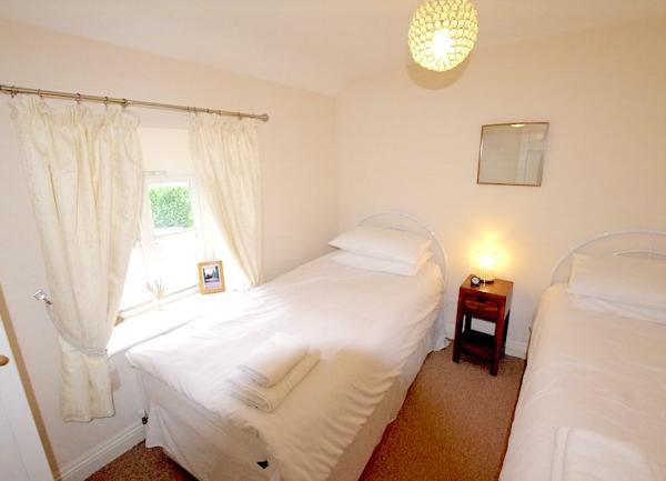 Twin bedroom with bedside cabinet with a table lamp.