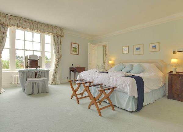 Double bedroom with bed, bedside cabinets with table lights and large windows with garden views.