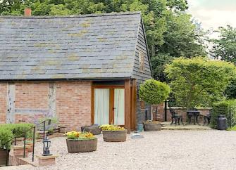 A Shropshire barn conversion with French windows and flower tubs in the shingled garden