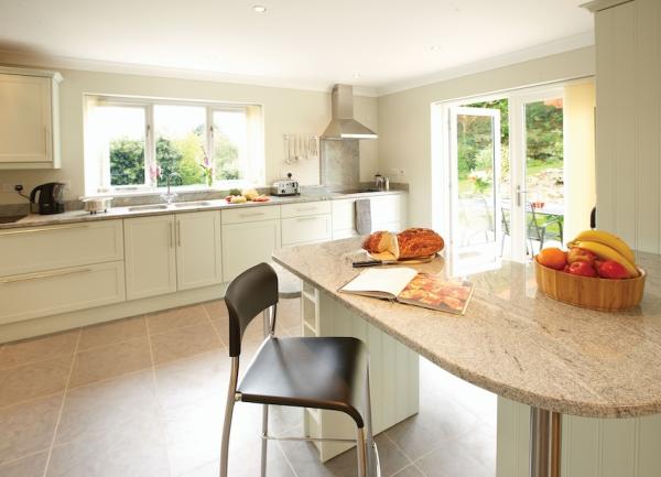 A fitted kitchen with marble topped worktops and French windows to a garden.