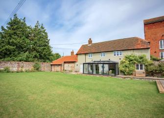 A wisteria-clad cottage with a sun-room overlooks a spacious lawn and terrace.