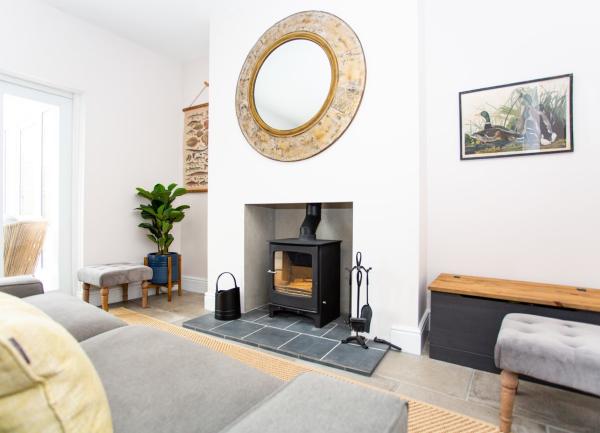 A Norfolk country cottage lounge with sofa and wood-burner.