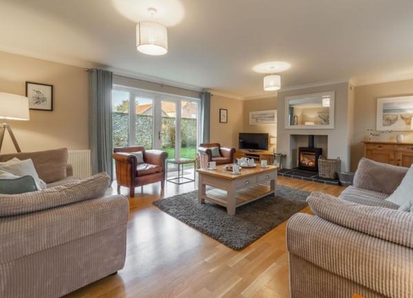 A pine-floored, spacious lounge with high-quality sofa and armchairs.
