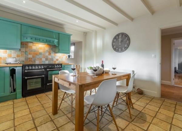 A fitted kitchen with cupboard and matching shelves, dishwasher and range cooker.