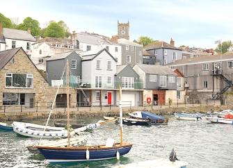 Former fishing lofts and fisherrmans cottages overlook a quayside with small craft moored in the harbour.