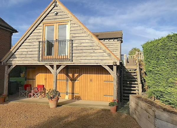 Exterior view of a gable end cottage with French windows and a Juliet balcony.