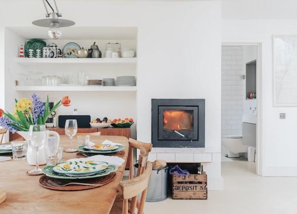 Dining arera with dinner table laid for tea and a wood-burner