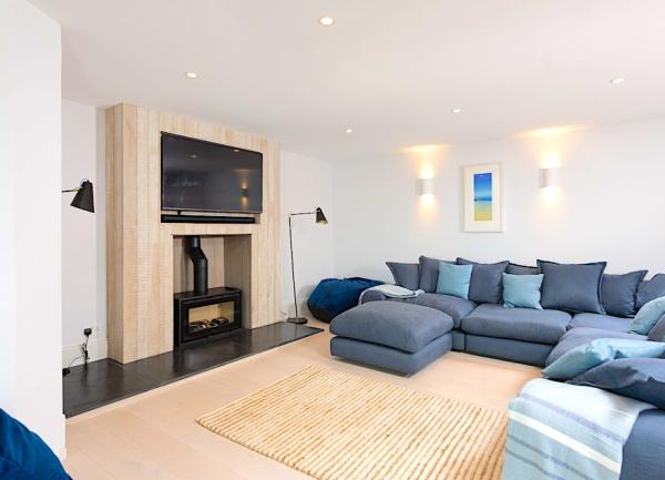 A lounge with a wrap-around sofa, wood burner and large widescreen TV.