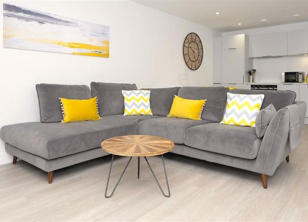 A lounge with sofa and coffee table with a fitted kitchen behind it.