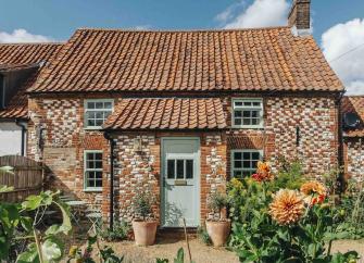 An ornate brick-built detached Kings Lynn holiday cottage overlooking a flower-filled garden. 