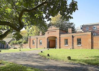 An arched brick gatehouse converted to holiday cottages.