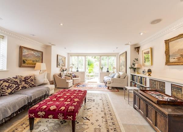 A long, luxurious lounge with French windows, sofas and armchairs. 