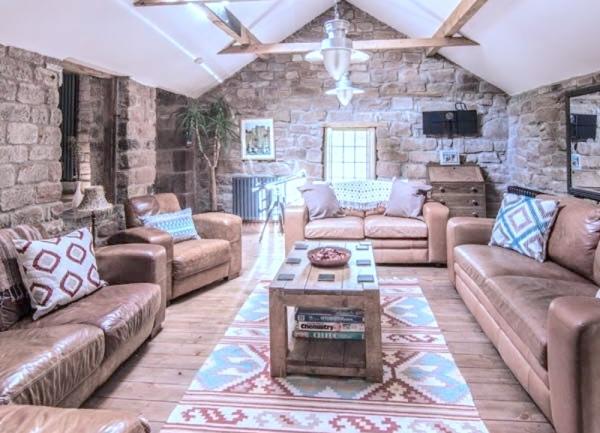 A sumptuous lounge with exposed stone walls and soft leather sofas