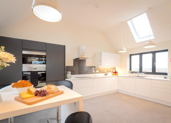Spacious modern kitchen with mid-height oven and breakfast bar.