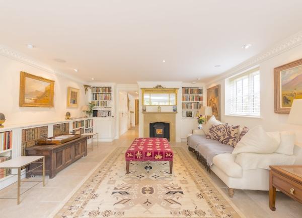 a lounge with rows of built-in bookshelves, sofas and a wood-burner.
