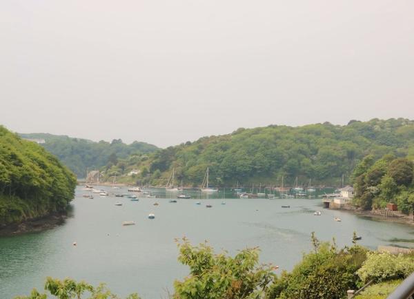 A wide estuary winds through steep, wooded hills.