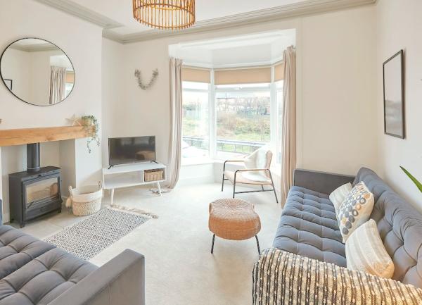 Spacious, bay-windowed living room with large sofas, widescreen TV and wood-burner.